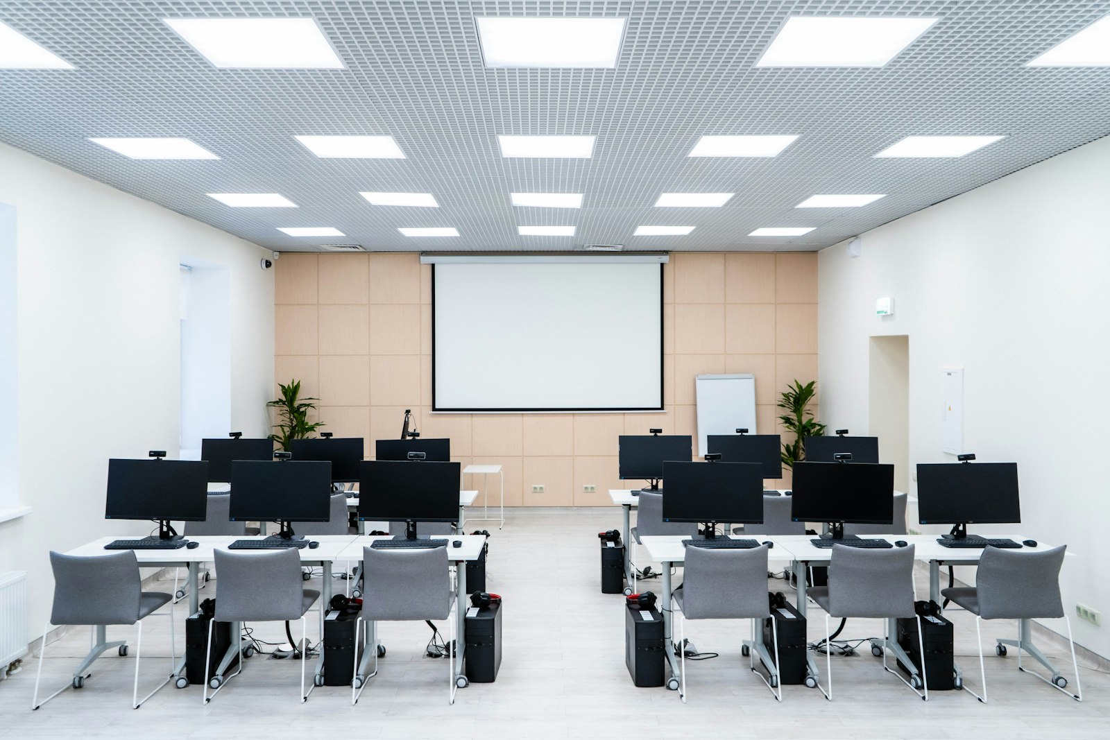 An exam hall laid out with rows of computers, a webcam on each monitor