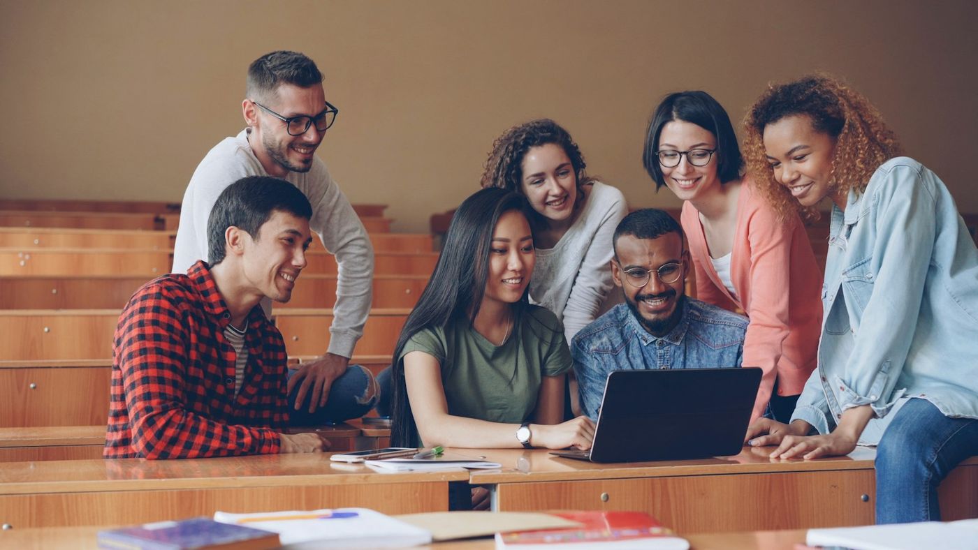 A group of learners gathered around a laptop